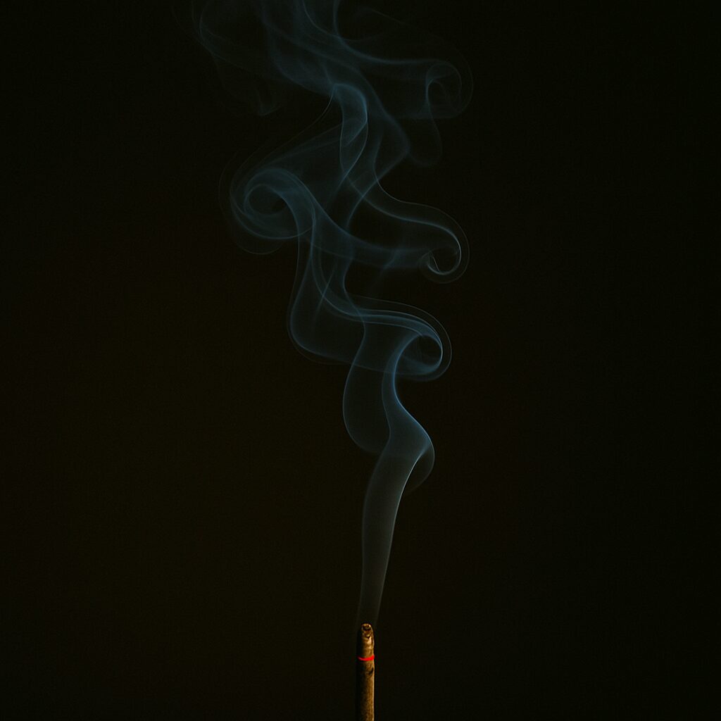 A single stick of incense releasing soft, curling